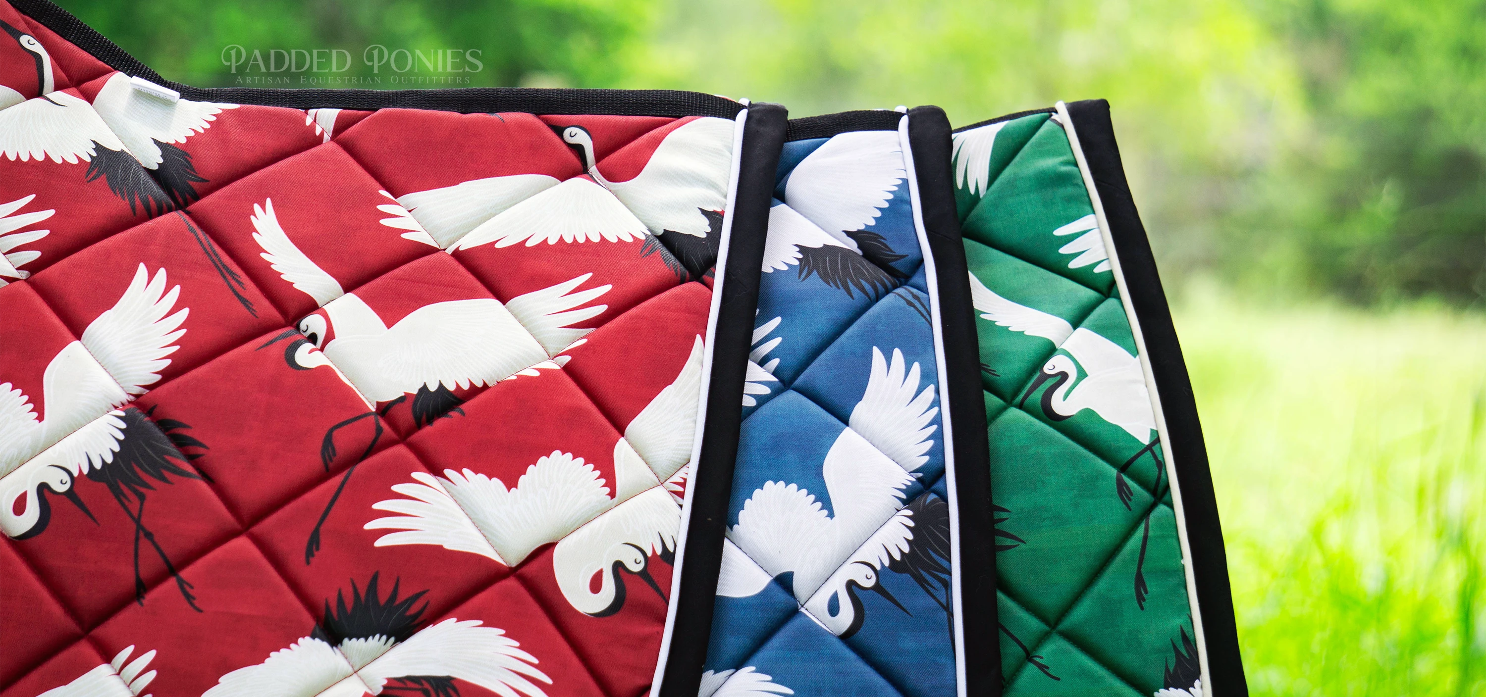 Custom Cranes Design Saddle Pads In Red, Blue, and Green.